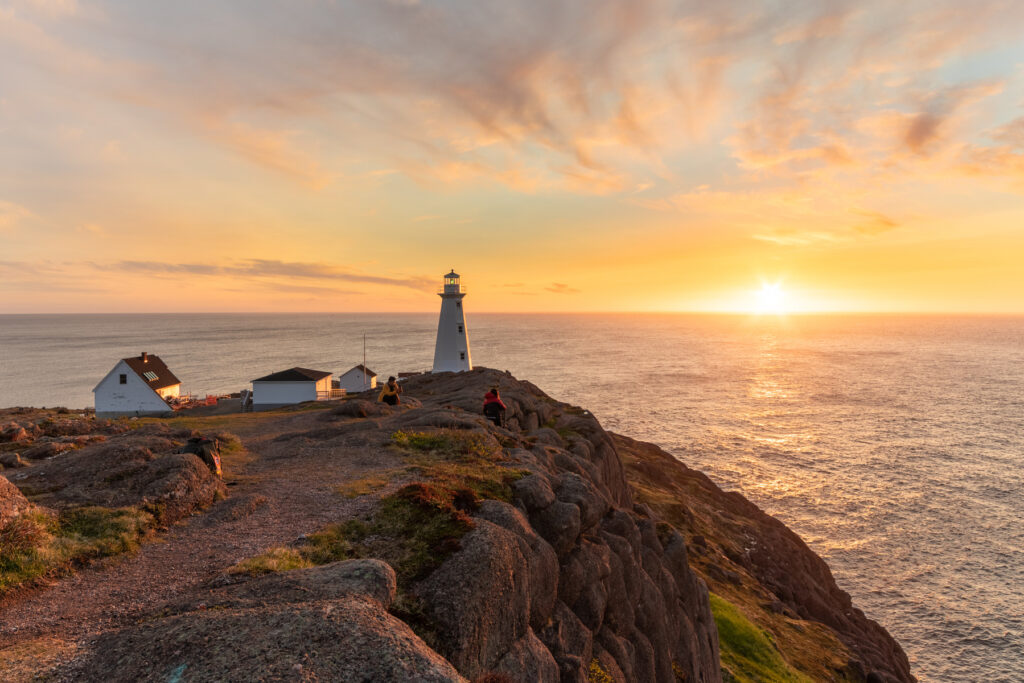 Beautiful sunrise over a white lighthouse sitting at the edge of a rocky cliff at Cape Spear