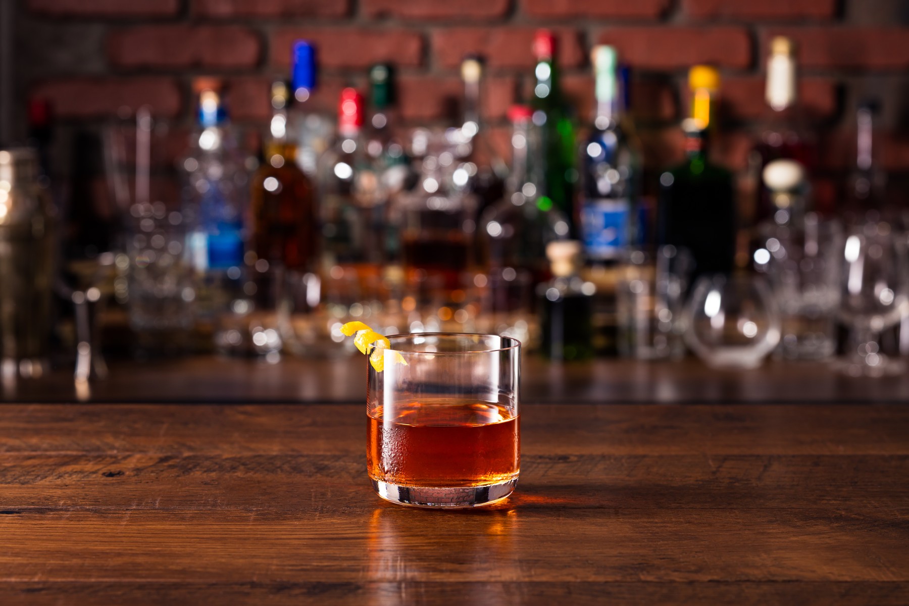 Sazerac cocktail served on a bar with an orange peel garnish