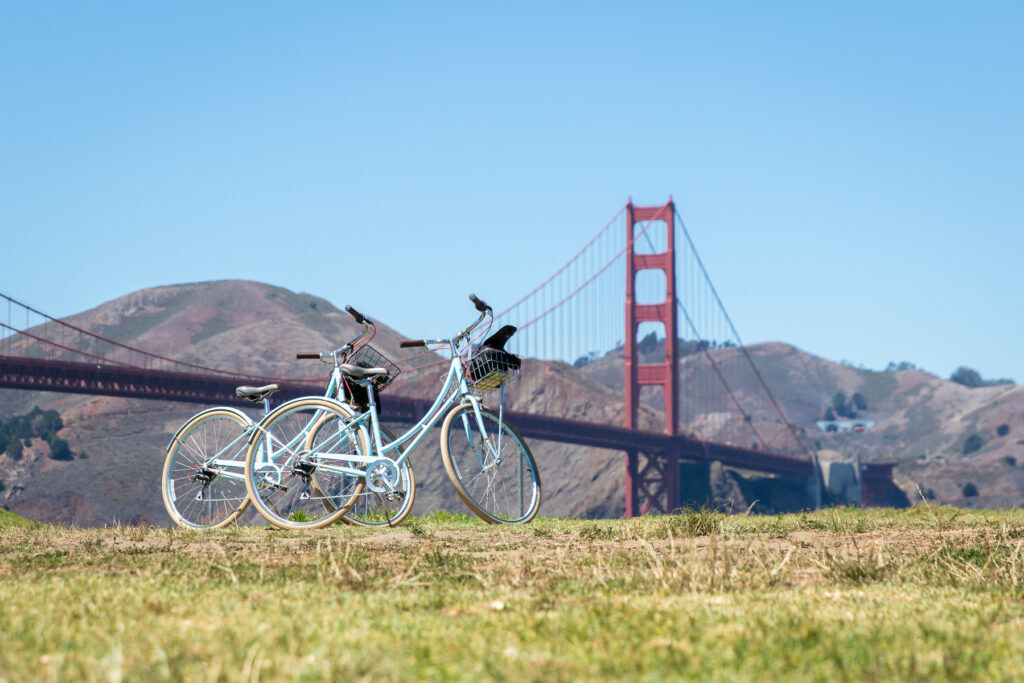 Two bicycles parked on grass in front of Golden Gate Bridge