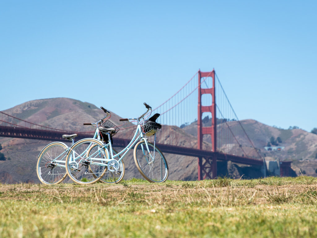 Two bicycles parked on grass in front of Golden Gate Bridge